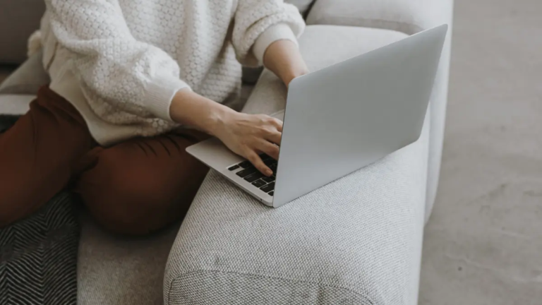 A clinician sitting on the couch working on her laptop