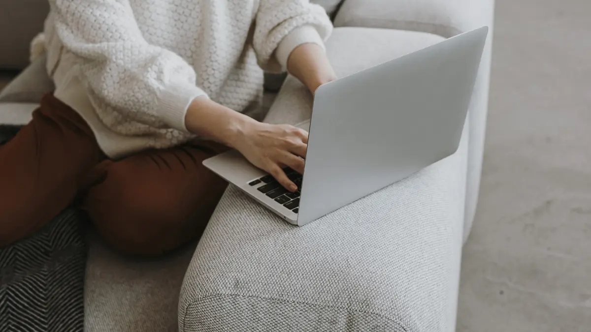 A clinician sitting on the couch working on her laptop