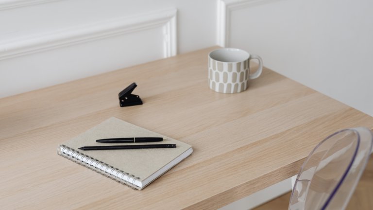 Beige desk set-up with a white coffee mug and notebook with notes about how to start a website on a budget as a private practice owner