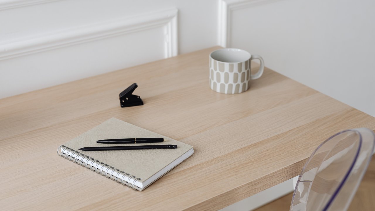 Beige desk set-up with a white coffee mug and notebook with notes about how to start a website on a budget as a private practice owner
